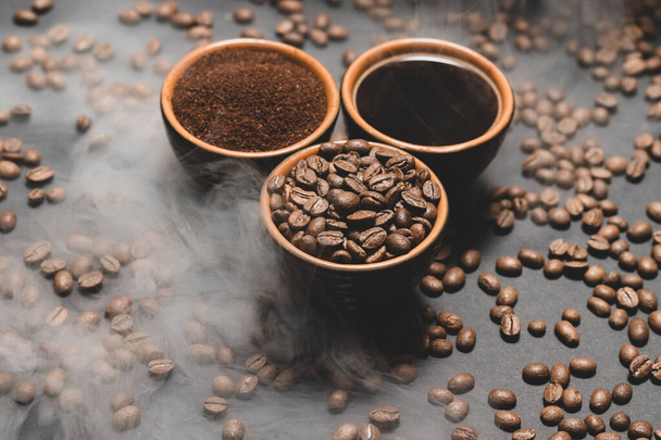Set of three cups of coffee beans, ground and drink on black background, top view of coffee. - Photo, Image