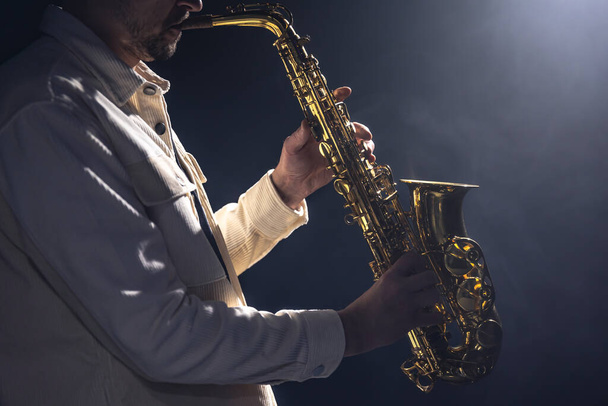 Musicien masculin sur scène joue le saxophone sombre avec de la fumée, espace de copie. - Photo, image