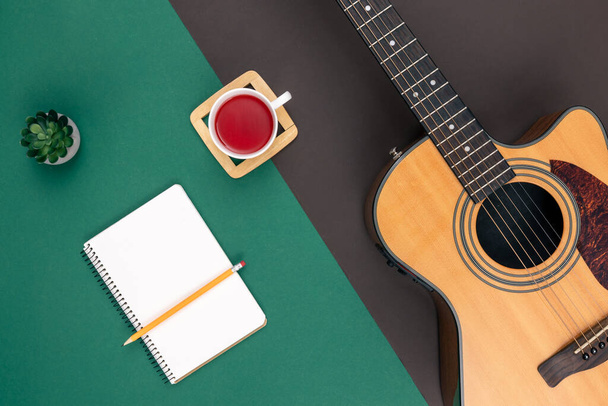 Flat lay, acoustic guitar, cup of tea and notebook on color background. - Photo, Image