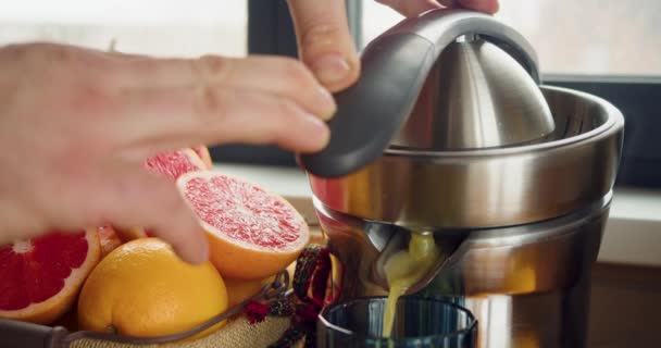 Männliche Hände pressen Grapefruitsaft auf eine Saftpresse. Nahaufnahme. 4k Filmmaterial. - Filmmaterial, Video