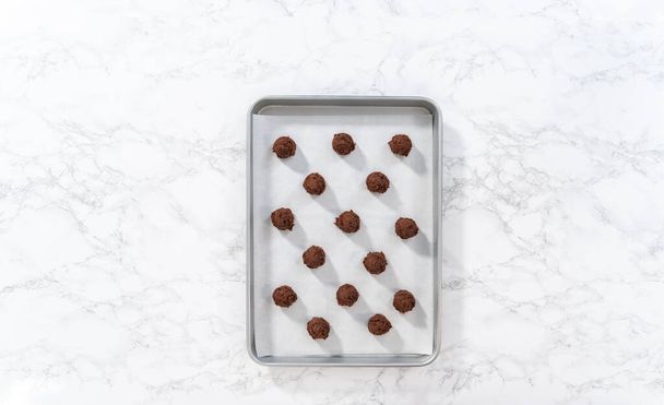 Flat lay. Scooping cookie dough with dough scoop into a baking sheet lined with parchment paper to bake chocolate cookies with chocolate hearts for Valentines Day. - Photo, Image