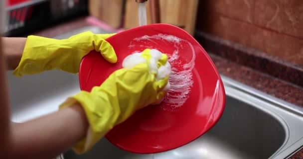 Gros plan des mains en gants de caoutchouc jaune nettoyant lavant la vaisselle dans l'évier de cuisine. Vie familiale - Séquence, vidéo