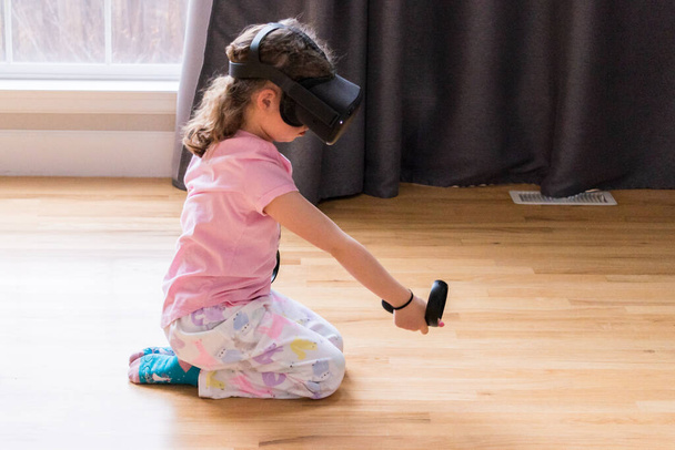 Küçük kız oturma odasında sanal gerçeklik oyunu oynuyor., - Fotoğraf, Görsel