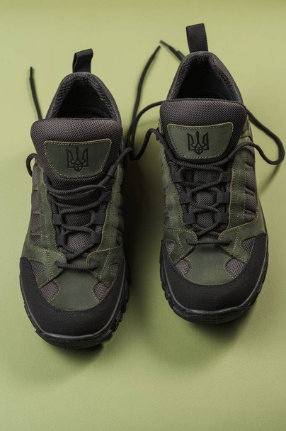 Military sneakers on a green background. Khaki army shoes - Фото, изображение