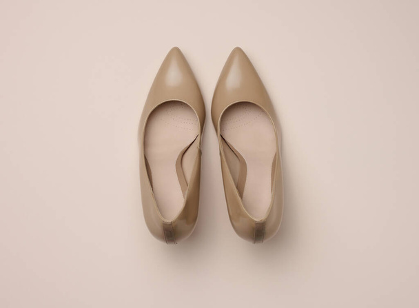 Leather beige high heel shoes on a beige background, top view. - Photo, Image