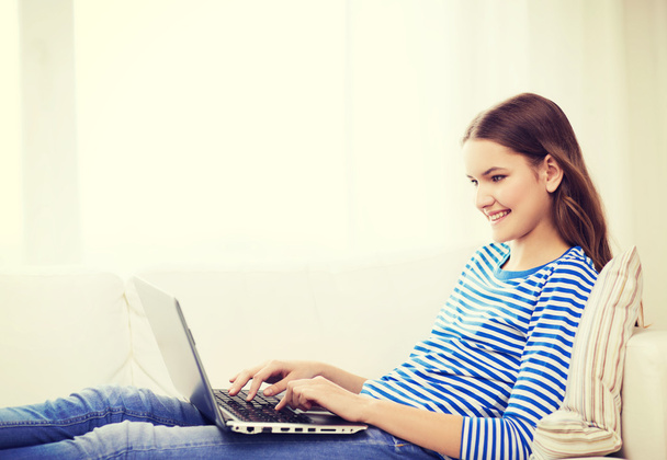 smiling teenage girl with laptop computer at home - 写真・画像
