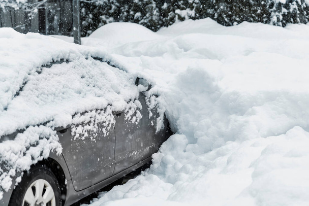 Şehir caddesindeki otoparkın önünde kar yağışı sonrası kar yağışı yüzünden yoğun kar yağışı nedeniyle sıkışmış bir SUV arabası var. Kar yığınları ve donmuş araçlar. Aşırı hava koşulları. - Fotoğraf, Görsel