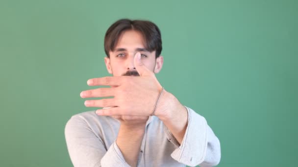 Bärtiger junger Mann zeigt mit dem Finger auf den Handrücken vor dem Chroma-Schlüssel, Gesichtsausdruck lächelnd, Zeigefinger wie Geschenk - Filmmaterial, Video