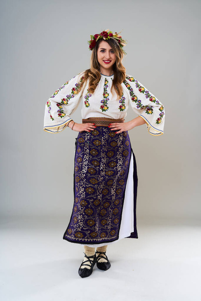 Nuori nainen suosittu vuosikerta perinteinen Romanian puku, eristetty harmaalla pohjalla - Valokuva, kuva
