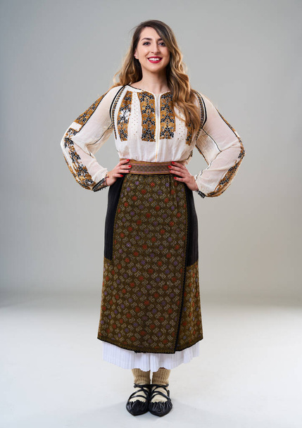 Young woman in popular vintage traditional Romanian costume, isolated on gray background - Fotoğraf, Görsel