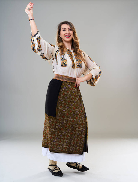 Young woman in popular vintage traditional Romanian costume, isolated on gray background - Zdjęcie, obraz