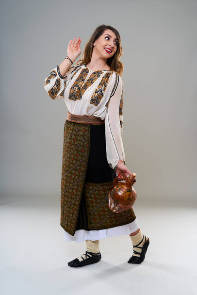 Young woman in popular vintage traditional Romanian costume, isolated on gray background - Photo, image