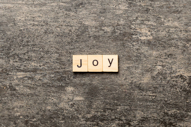 Palabra de alegría escrita en madera. Texto de la alegría en la mesa de cemento para su diseño, concepto
. - Foto, imagen