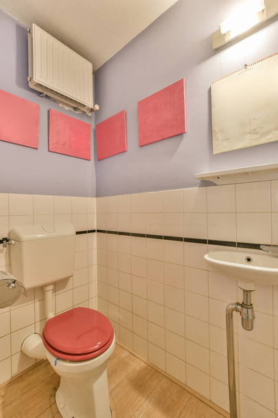a bathroom with pink and white tiles on the wall above the toilet is next to a sink thats not in use - Фото, изображение