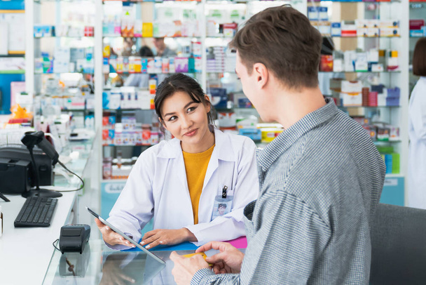 Payment by credit card with payment terminal in qualified drugstore. Modern financial payment of electric money. Caucasian customer purchase medication in pharmacy with prescription from pharmacist. - Photo, Image