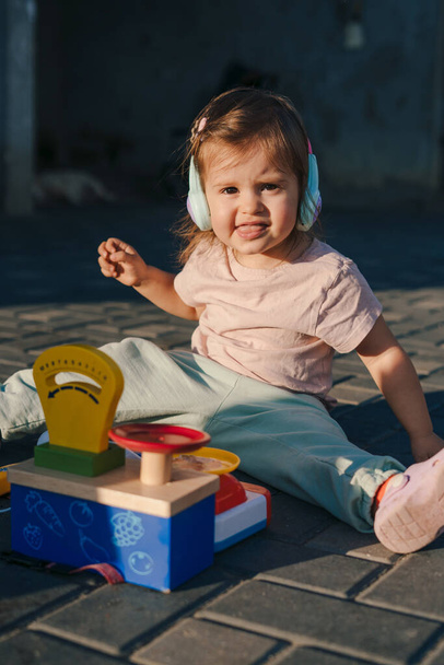 Bébé fille debout à l'extérieur sur la terrasse jouant avec un jouet coloré et attrayant pour les enfants. Apprendre par l'activité de jeu pour le développement des enfants. - Photo, image