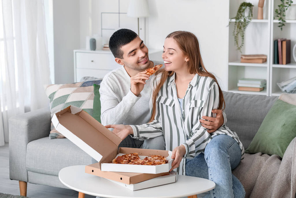 Glückliches junges Paar isst leckere Pizza zu Hause - Foto, Bild