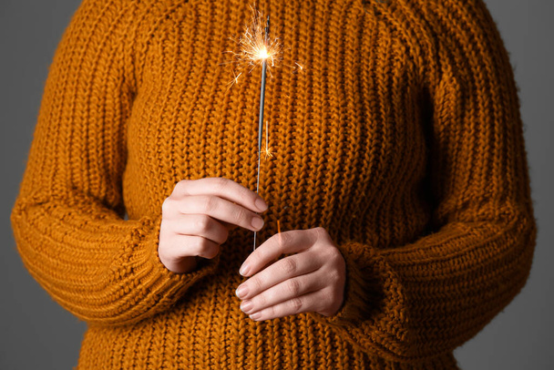 Femme en pull tricoté avec scintillement de Noël sur fond sombre, gros plan - Photo, image