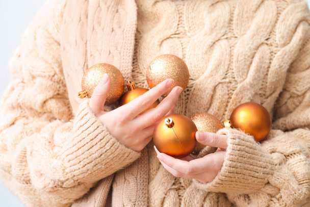 Woman in beige sweater with golden Christmas balls, closeup - Photo, Image