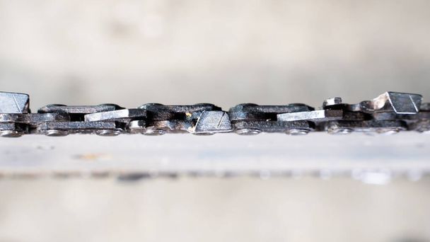 Primer plano de una cadena de motosierra en un neumático sobre un fondo borroso, vista superior - Foto, Imagen