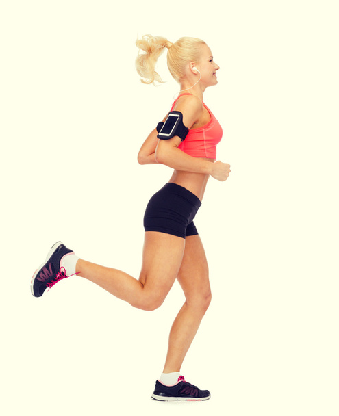 sporty woman running with smartphone and earphones - Foto, Imagem