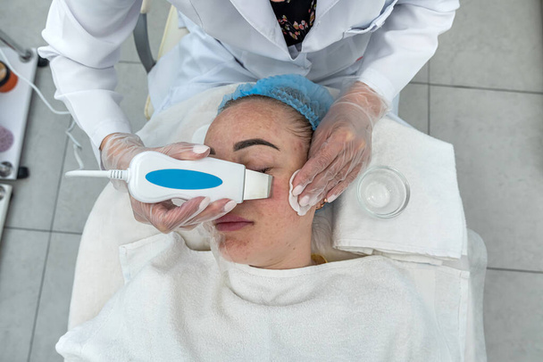 estetista in guanti fa un trattamento viso con una spatola ultrasonica per una donna. trattamento della pelle del viso con uno scrubber utilizzando una spatola ultrasonica. procedura di pulizia del viso in un salone di bellezza - Foto, immagini