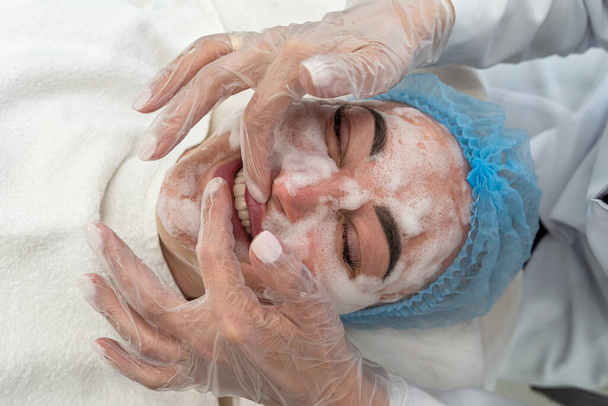 professionelle Kosmetikerin führt eine Ultraschallreinigung der Gesichtshaut mit Hilfe eines Gerätes durch. Kosmetischer Eingriff im Salon der Schönheitsklinik. Das Konzept der Maschinenkosmetologie. - Foto, Bild