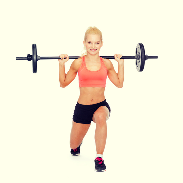 smiling sporty woman exercising with barbell - Foto, immagini