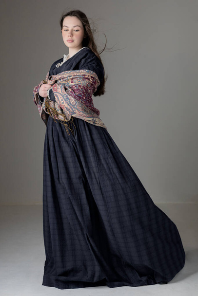 Una joven mujer victoriana con un vestido de algodón azul con ribete de encaje vintage en un fondo de estudio - Foto, imagen
