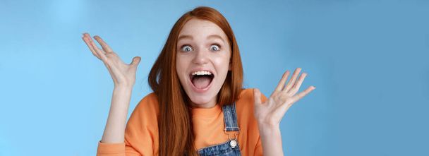 Surprised astonished sensitive overwhelmed young happy redhead girl receive incredible fantastic prize wide eyes astonished raising hands triumphing win lottery celebrating joyfully. - Photo, Image