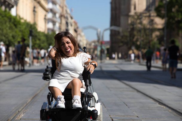 bela jovem deficiente mulher em cadeira de rodas e mobilidade reduzida goza de sua viagem ao redor da cidade onde ela está de férias. - Foto, Imagem