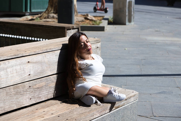 bela jovem deficiente mulher em cadeira de rodas e mobilidade reduzida sentado em um banco de parque desfrutando do dia ensolarado. - Foto, Imagem