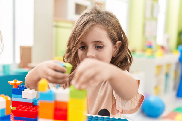 Adorável menina hispânica brincando com blocos de construção sentados na mesa no jardim de infância - Foto, Imagem