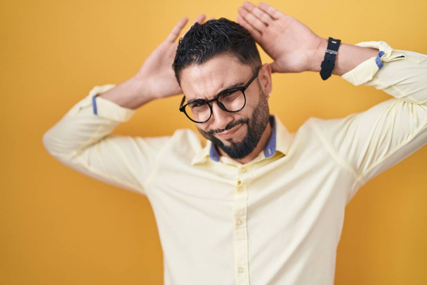 Hispanic young man wearing business clothes and glasses doing bunny ears gesture with hands palms looking cynical and skeptical. easter rabbit concept.  - Photo, Image