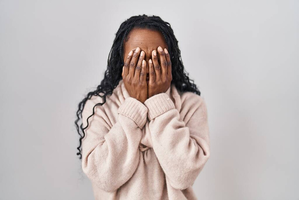 Mujer africana de pie sobre fondo blanco frotando los ojos para la fatiga y el dolor de cabeza, la expresión somnolienta y cansada. problema de visión  - Foto, imagen
