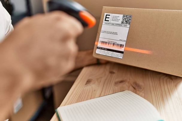 Jonge Spaanse man scannen pakket label met barcode lezer bij storehouse - Foto, afbeelding