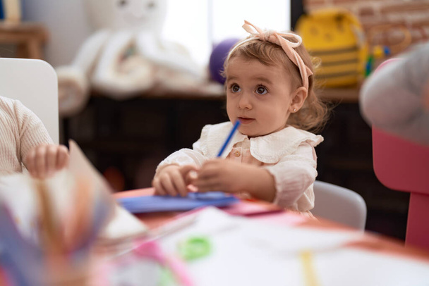 Adorable caucasian girl preschool student drawing on paper standing at kindergarten - Valokuva, kuva