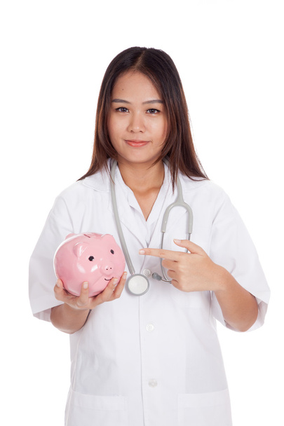 Young Asian female doctor point to a pig bank coin - Zdjęcie, obraz