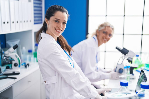 Две женщины-учёные, работающие в лаборатории под микроскопом - Фото, изображение