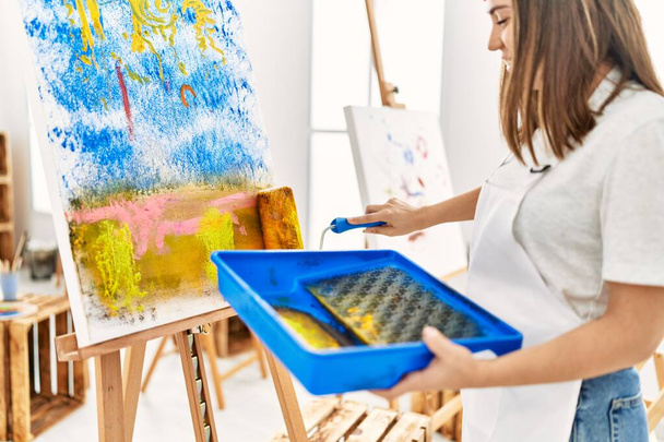 Fransız beresi takan genç İspanyol sanatçı resim stüdyosunda boya silindiri kullanıyor.. - Fotoğraf, Görsel