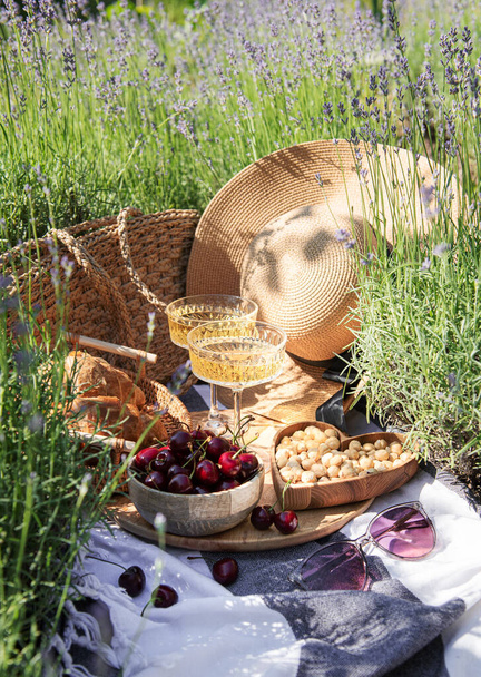 Summer picnic on a lavender field with champagne glasses and cherry berries - Foto, Imagen