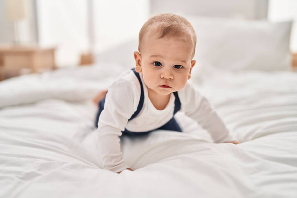 Liebenswertes Kleinkind krabbelt auf Bett im Schlafzimmer - Foto, Bild