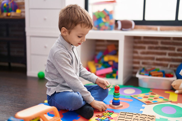Αξιολάτρευτο παιδί παίζει με μαθηματικά παιχνίδι κάθεται στο πάτωμα στο νηπιαγωγείο - Φωτογραφία, εικόνα