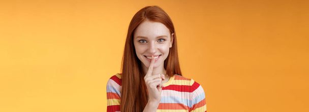 Flirty devious creative young redhead smiling excited ginger girl prepare mysterious gift surprise party giggling tricky say shush shhh gesture index finger mouth grinning delighted, have idea. - Photo, Image