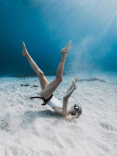 Девушка-фридайвер играет с песком на глубоководье. Фридайвинг в голубом море - Фото, изображение