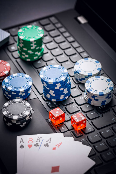 Online poker. Chips, cards and dice nearby keyboard. Betting services on Internet. Gambling on website and winning money. Play poker online at home. - Photo, Image
