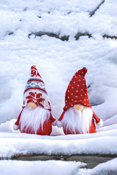 クリスマスの休日カード雪の冬のベンチに赤い帽子と白いひげを持つかわいいスカンディナヴィアのノームおとぎ話の雪の冬こんにちは12月, 1月, 2月のコンセプトハッピーニューイヤー,クリスマス. - 写真・画像