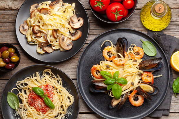 Diverse Italiaanse pasta. Zeevruchten, champignons en tomatensaus pasta, spaghetti bolognese. Bovenaanzicht vlak lay - Foto, afbeelding