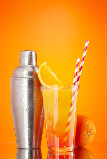 Cocktail shaker and tequila sunrise cocktail on orange background with copy space - Photo, Image