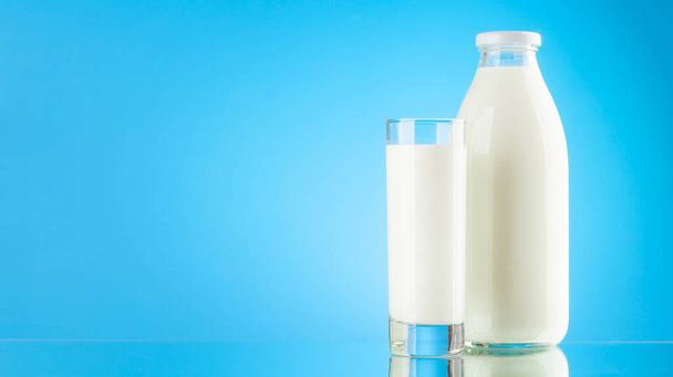 Süt şişesi ve cam, mavi arkaplanda fotokopi alanı var. Süt ürünü - Fotoğraf, Görsel
